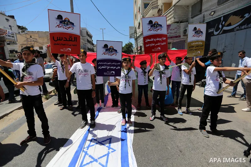 Palestinian Scout youths wave a large Palestinian flag and step on the Israeli flag in a protest marking the annual al-Quds Day, or Jerusalem Day, following Friday prayer in Gaza city June 23, 2017. Photo by Ashraf Amra