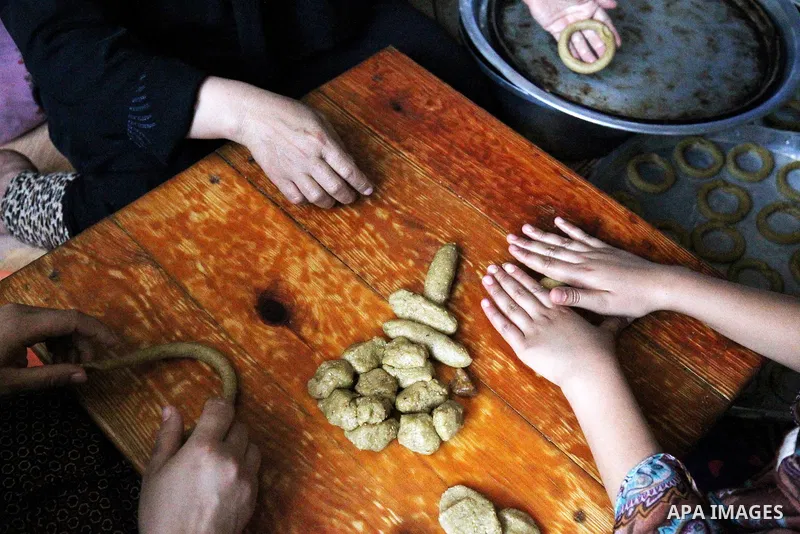 A Palestinian family make traditional date-filled cookies in preparation for the Eid al-Fitr holiday at their home in Rafah, in the southern Gaza Strip, on June 23, 2017. Muslims around the world are preparing to celebra...