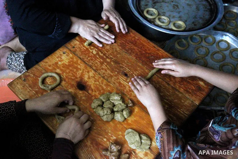 A Palestinian family make traditional date-filled cookies in preparation for the Eid al-Fitr holiday at their home in Rafah, in the southern Gaza Strip, on June 23, 2017. Muslims around the world are preparing to celebra...