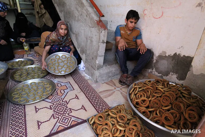 A Palestinian family make traditional date-filled cookies in preparation for the Eid al-Fitr holiday at their home in Rafah, in the southern Gaza Strip, on June 23, 2017. Muslims around the world are preparing to celebra...