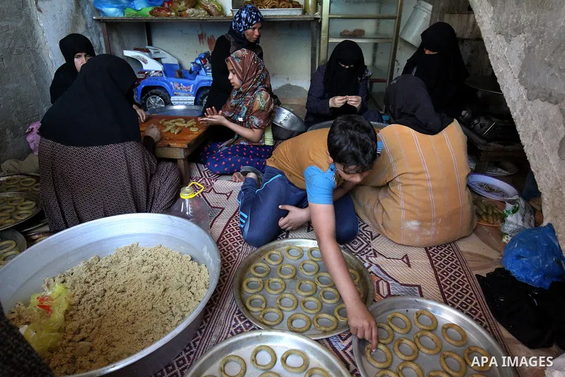 A Palestinian family make traditional date-filled cookies in preparation for the Eid al-Fitr holiday at their home in Rafah, in the southern Gaza Strip, on June 23, 2017. Muslims around the world are preparing to celebra...