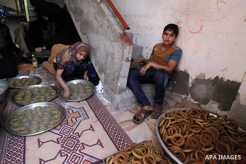 A Palestinian family make traditional date-filled cookies in preparation for the Eid al-Fitr holiday at their home in Rafah, in the southern Gaza Strip, on June 23, 2017. Muslims around the world are preparing to celebra...