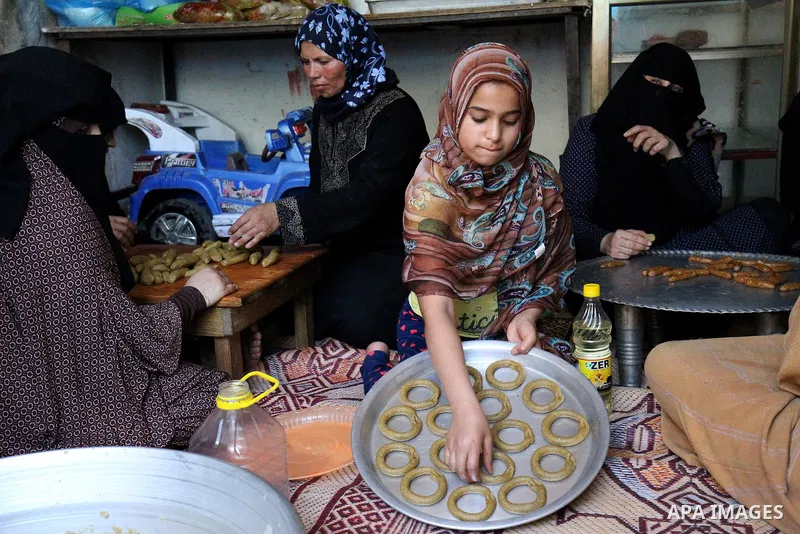 A Palestinian family make traditional date-filled cookies in preparation for the Eid al-Fitr holiday at their home in Rafah, in the southern Gaza Strip, on June 23, 2017. Muslims around the world are preparing to celebra...