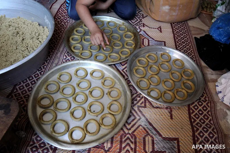 A Palestinian family make traditional date-filled cookies in preparation for the Eid al-Fitr holiday at their home in Rafah, in the southern Gaza Strip, on June 23, 2017. Muslims around the world are preparing to celebra...