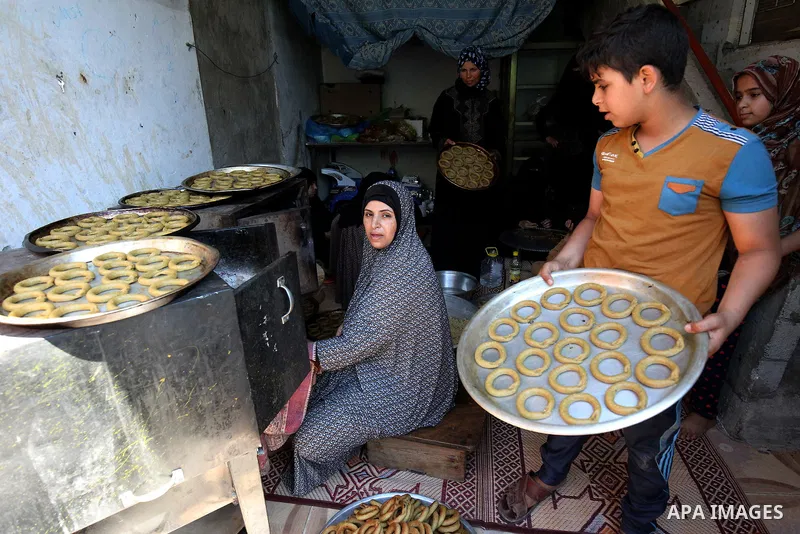A Palestinian family make traditional date-filled cookies in preparation for the Eid al-Fitr holiday at their home in Rafah, in the southern Gaza Strip, on June 23, 2017. Muslims around the world are preparing to celebra...