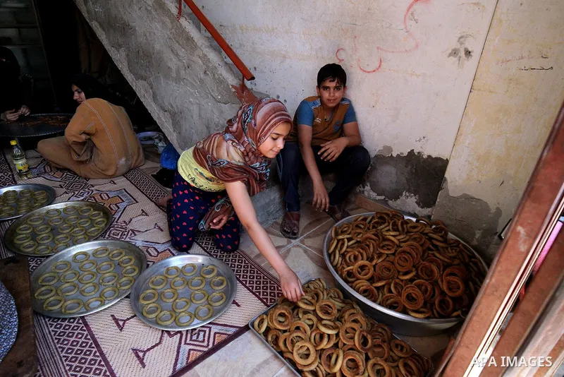 A Palestinian family make traditional date-filled cookies in preparation for the Eid al-Fitr holiday at their home in Rafah, in the southern Gaza Strip, on June 23, 2017. Muslims around the world are preparing to celebra...