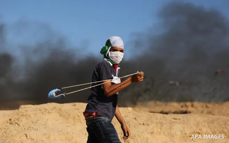 A Palestinian protester uses a slingshot to hurl stones toward Israeli security forces during clashes near the border between Israel and Central Gaza Strip east of Bureij on June 23, 2017. Photo by Ashraf Amra