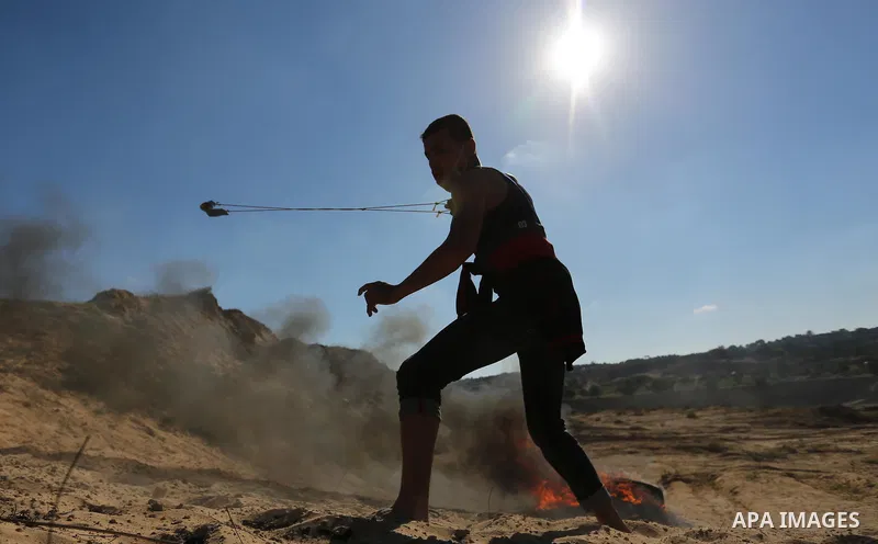 A Palestinian protester uses a slingshot to hurl stones toward Israeli security forces during clashes near the border between Israel and Central Gaza Strip east of Bureij on June 23, 2017. Photo by Ashraf Amra
