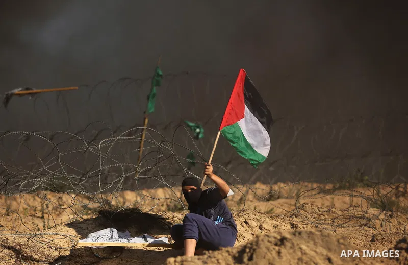 A Palestinian protester waves the national flag during clashes with Israeli security forces near the border between Israel and Central Gaza Strip of Bureij on June 23, 2017. Photo by Ashraf Amra