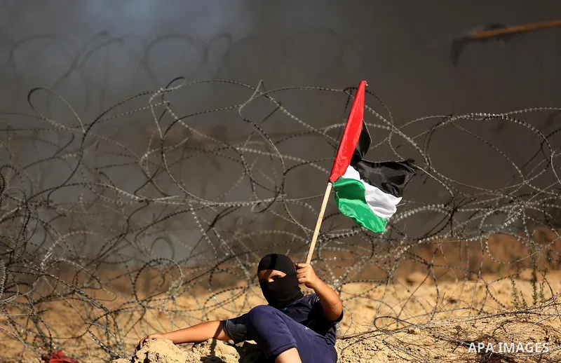 A Palestinian protester waves the national flag during clashes with Israeli security forces near the border between Israel and Central Gaza Strip of Bureij on June 23, 2017. Photo by Ashraf Amra