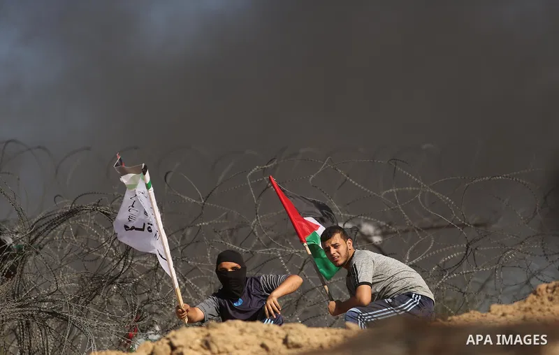 Palestinian protesters wave the national flag during clashes with Israeli security forces near the border between Israel and Central Gaza Strip of Bureij on June 23, 2017. Photo by Ashraf Amra