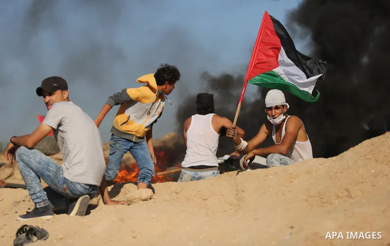 Palestinian protesters wave the national flag during clashes with Israeli security forces near the border between Israel and Central Gaza Strip of Bureij on June 23, 2017. Photo by Ashraf Amra