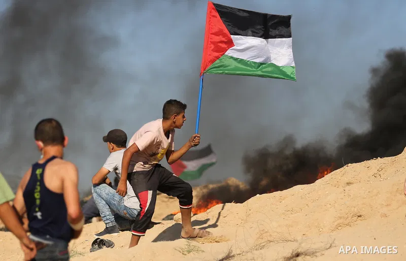 Palestinian protesters wave the national flag during clashes with Israeli security forces near the border between Israel and Central Gaza Strip of Bureij on June 23, 2017. Photo by Ashraf Amra