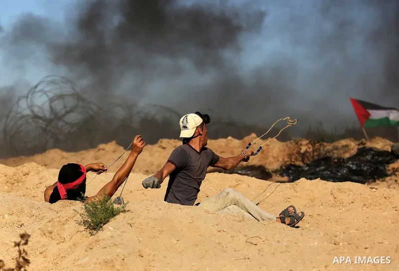 Palestinian protesters wave the national flag during clashes with Israeli security forces near the border between Israel and Central Gaza Strip of Bureij on June 23, 2017. Photo by Ashraf Amra