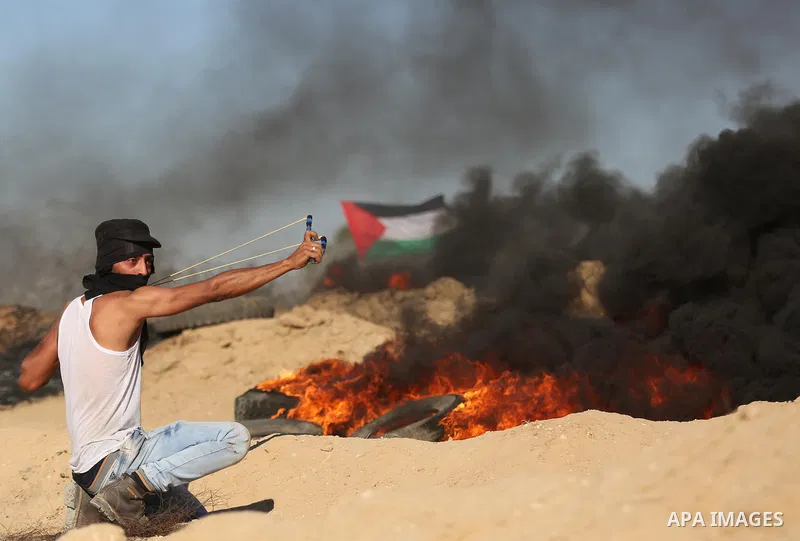 Palestinian protesters wave the national flag during clashes with Israeli security forces near the border between Israel and Central Gaza Strip of Bureij on June 23, 2017. Photo by Ashraf Amra