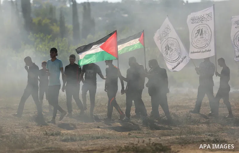 Palestinian protesters wave the national flag during clashes with Israeli security forces near the border between Israel and Central Gaza Strip of Bureij on June 23, 2017. Photo by Ashraf Amra