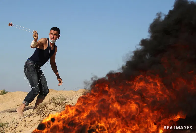 A Palestinian protester uses a slingshot to hurl stones toward Israeli security forces during clashes near the border between Israel and Central Gaza Strip east of Bureij on June 23, 2017. Photo by Ashraf Amra