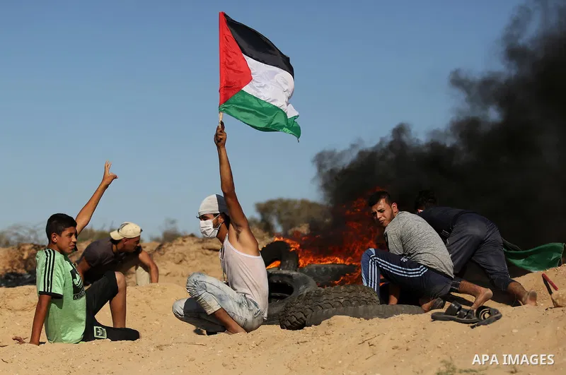 Palestinian protesters wave the national flag during clashes with Israeli security forces near the border between Israel and Central Gaza Strip of Bureij on June 23, 2017. Photo by Ashraf Amra