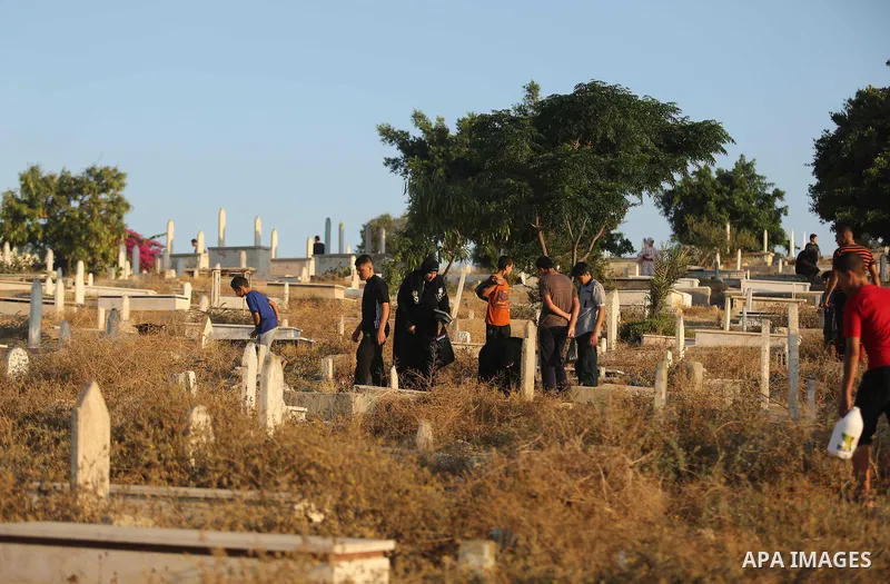 Palestinians visit the grave of their relative on the first day of Eid al-Fitr prayers, at a cemetery in Gaza City June 25, 2017. Photo by Ashraf Amra