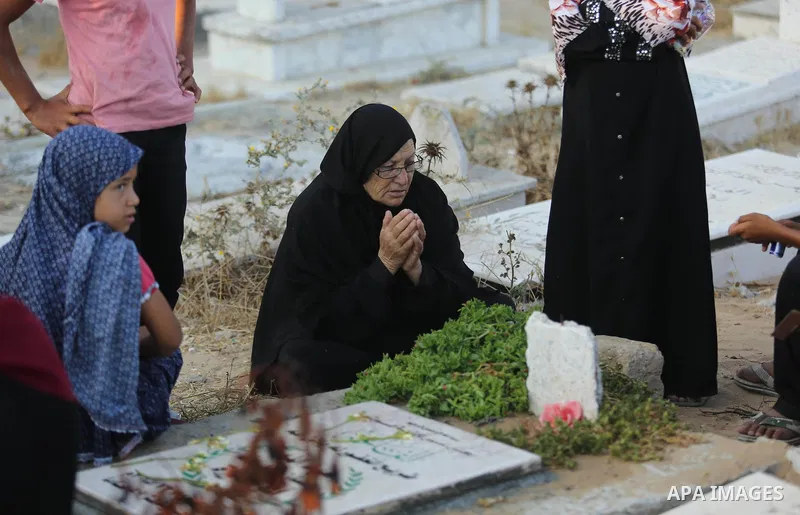 Palestinians visit the grave of their relative on the first day of Eid al-Fitr prayers, at a cemetery in Gaza City June 25, 2017. Photo by Ashraf Amra