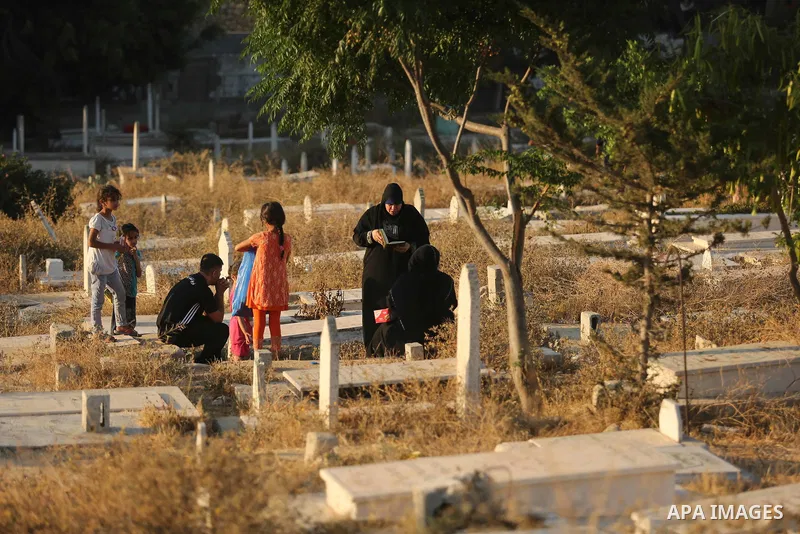 Palestinians visit the grave of their relative on the first day of Eid al-Fitr prayers, at a cemetery in Gaza City June 25, 2017. Photo by Ashraf Amra