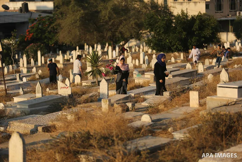 Palestinians visit the grave of their relative on the first day of Eid al-Fitr prayers, at a cemetery in Gaza City June 25, 2017. Photo by Ashraf Amra