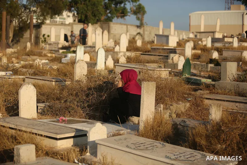 Palestinians visit the grave of their relative on the first day of Eid al-Fitr prayers, at a cemetery in Gaza City June 25, 2017. Photo by Ashraf Amra