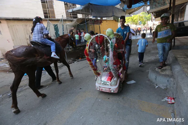 Palestinian children enjoy the first day of Eid al-Fitr holiday which marks the end of the Muslim holy month of Ramadan, in Gaza, on June 25, 2017. Photo by Mohammed Asad