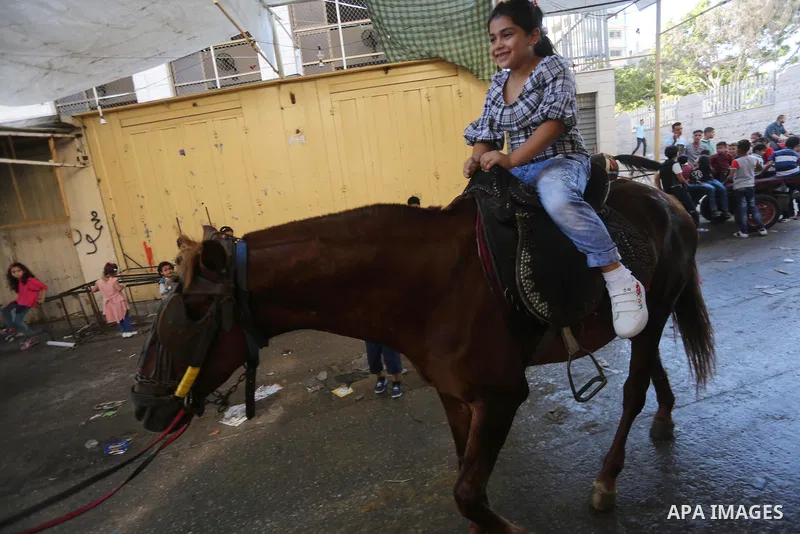 Palestinian children enjoy the first day of Eid al-Fitr holiday which marks the end of the Muslim holy month of Ramadan, in Gaza, on June 25, 2017. Photo by Mohammed Asad