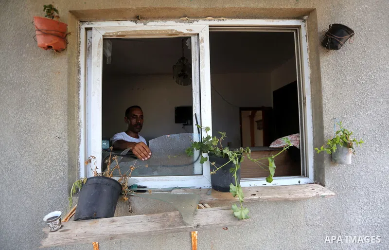 A Palestinian man removes broken glass from his window following an Israeli air strike in Gaza City on June 27, 2017. Israeli airstrikes hit a series of targets in the Hamas-run Gaza Strip overnight June 26, officials sa...