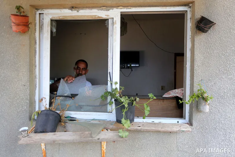 A Palestinian man removes broken glass from his window following an Israeli air strike in Gaza City on June 27, 2017. Israeli airstrikes hit a series of targets in the Hamas-run Gaza Strip overnight June 26, officials sa...