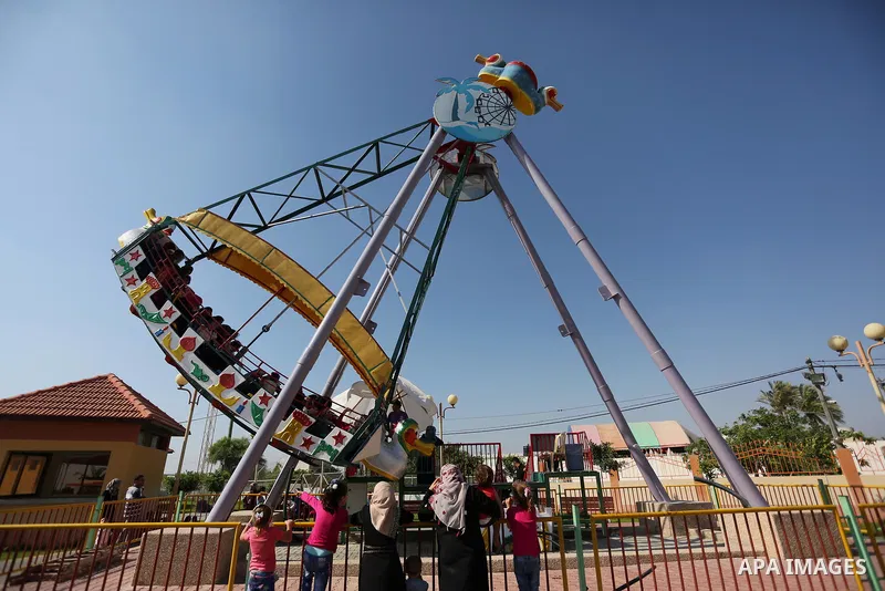 Palestinians take a ride at an amusement park on the third day of Eid al-Fitr holiday which marks the end of the Muslim holy month of Ramadan, in Gaza City on June 27, 2017. Photo by Ashraf Amra