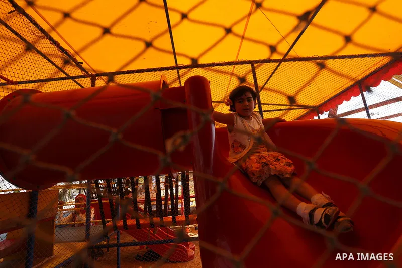 A Palestinian girl plays at an amusement park on the third day of Eid al-Fitr holiday which marks the end of the Muslim holy month of Ramadan, in Gaza City on June 27, 2017. Photo by Ashraf Amra