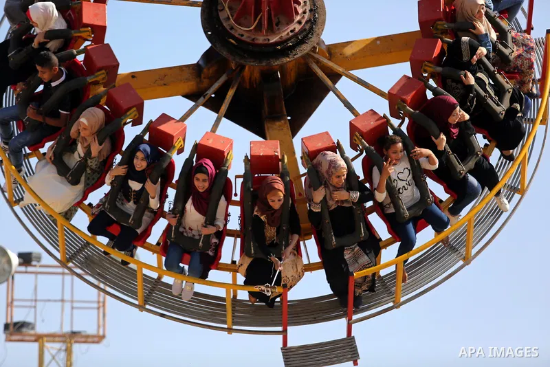 Palestinians take a ride at an amusement park on the third day of Eid al-Fitr holiday which marks the end of the Muslim holy month of Ramadan, in Gaza City on June 27, 2017. Photo by Ashraf Amra