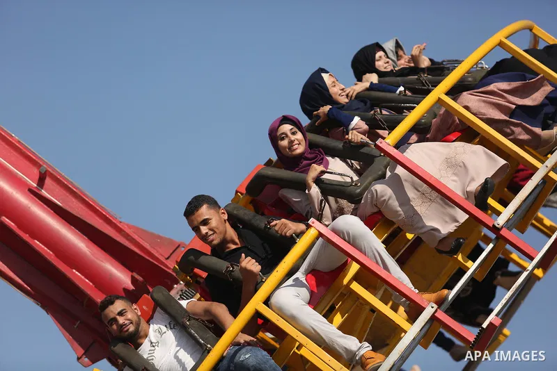 Palestinians take a ride at an amusement park on the third day of Eid al-Fitr holiday which marks the end of the Muslim holy month of Ramadan, in Gaza City on June 27, 2017. Photo by Ashraf Amra