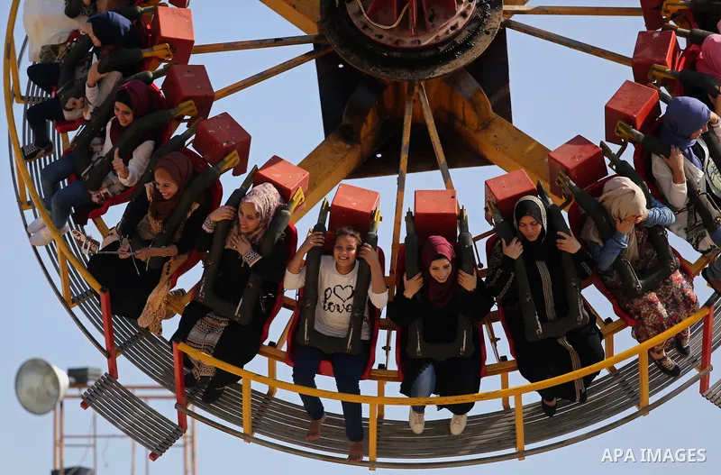 Palestinians take a ride at an amusement park on the third day of Eid al-Fitr holiday which marks the end of the Muslim holy month of Ramadan, in Gaza City on June 27, 2017. Photo by Ashraf Amra