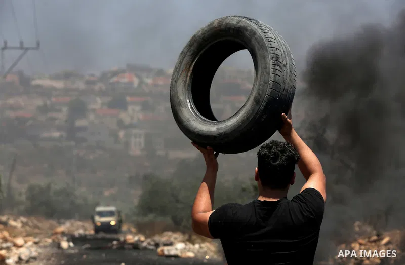 A Palestinian protester carries a tire during clashes with Israeli security forces following a weekly demonstration against the expropriation of Palestinian land by Israel in the village of Kfar Qaddum, near Nablus, in t...