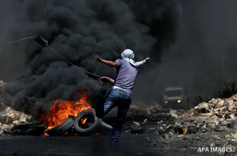 A Palestinian protester uses a slingshot to hurl stones towards Israeli security forces during clashes following a weekly demonstration against the expropriation of Palestinian land by Israel in the village of Kfar Qaddu...