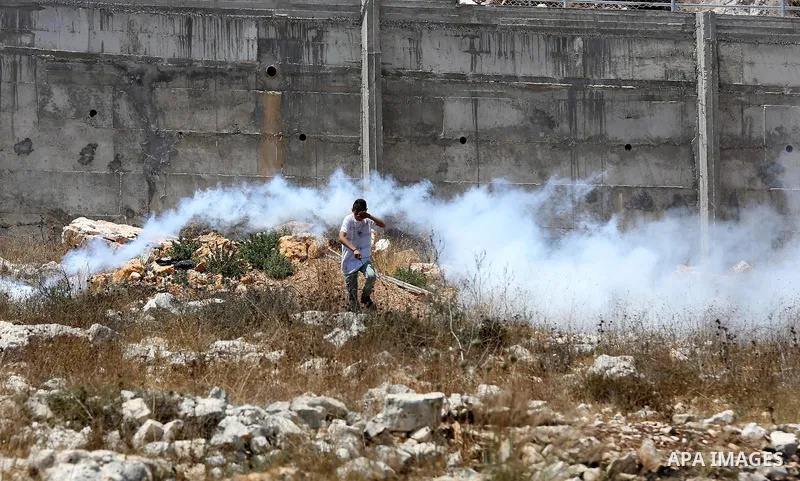A Palestinian protester takes cover during clashes with Israeli security forces following a weekly demonstration against the expropriation of Palestinian land by Israel in the village of Kfar Qaddum, near Nablus, in the...