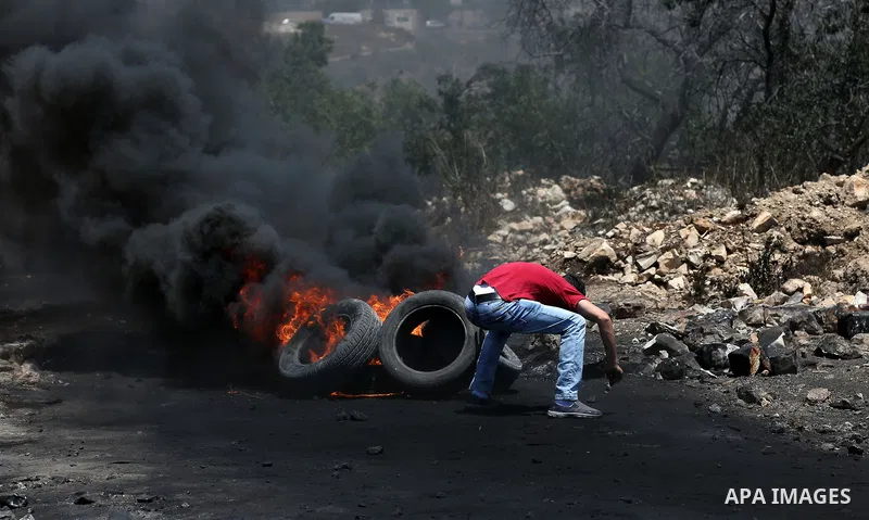 A Palestinian protester takes cover during clashes with Israeli security forces following a weekly demonstration against the expropriation of Palestinian land by Israel in the village of Kfar Qaddum, near Nablus, in the...
