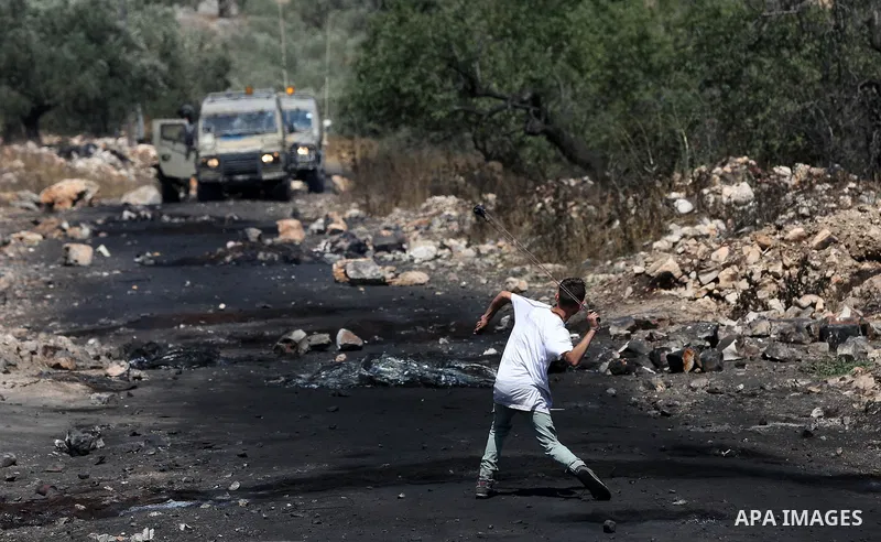 A Palestinian protester uses a slingshot to hurl stones towards Israeli security forces during clashes following a weekly demonstration against the expropriation of Palestinian land by Israel in the village of Kfar Qaddu...