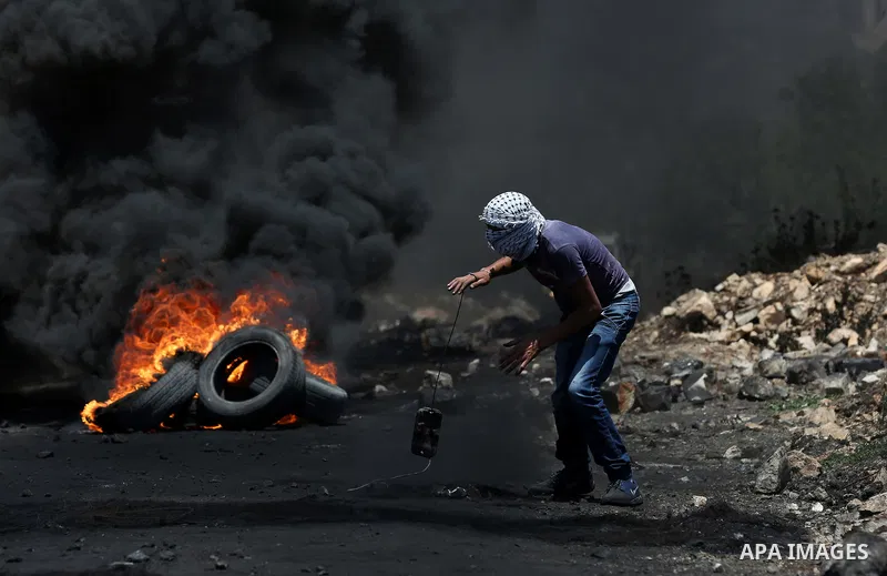 A Palestinian protester uses a slingshot to hurl stones towards Israeli security forces during clashes following a weekly demonstration against the expropriation of Palestinian land by Israel in the village of Kfar Qaddu...