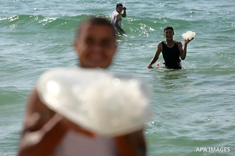 Palestinian men carry jellyfish at the beach of the Mediterranean sea on the coast of Deir el-Balah, Central Gaza Strip, on July 02, 2017. Photo by Ashraf Amra