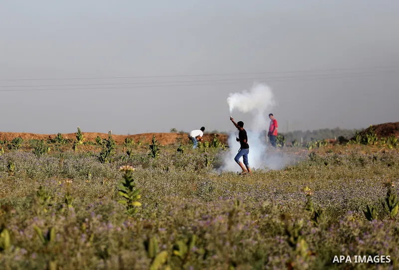 A Palestinian protester prepares to throw a tear gas canister fired by Israeli security forces during clashes near the border fence east of Gaza City, on July 02, 2017. Photo by Mohammed Asad