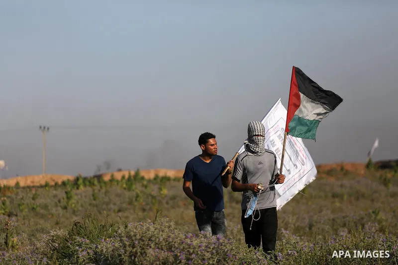 A Palestinian protester holds a national flag during clashes with Israeli security forces near the border fence east of Gaza City, on July 02, 2017. Photo by Mohammed Asad