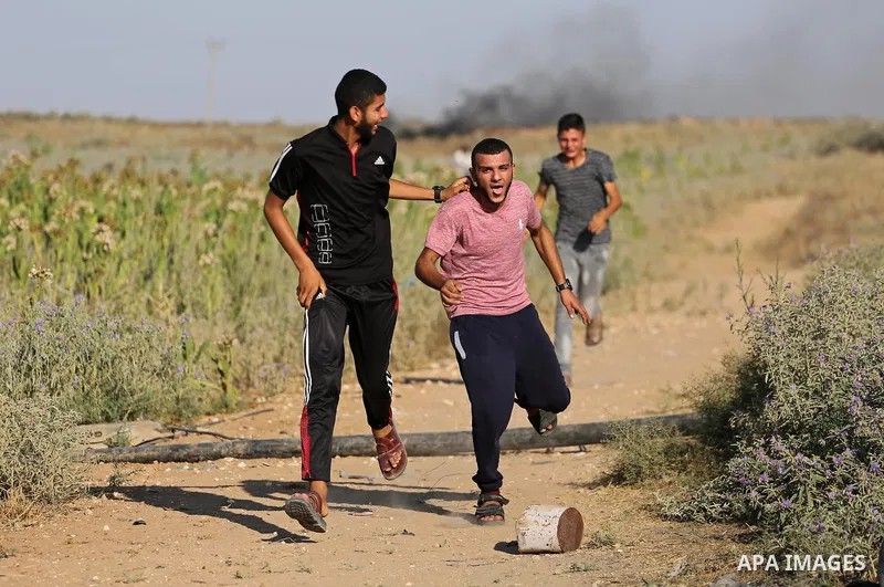 Palestinian protesters run for cover during clashes with Israeli security forces near the border fence east of Gaza City, on July 02, 2017. Photo by Mohammed Asad