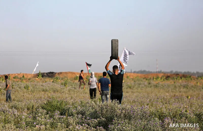 A Palestinian protester carries a tire during clashes with Israeli security forces near the border fence east of Gaza City, on July 02, 2017. Photo by Mohammed Asad
