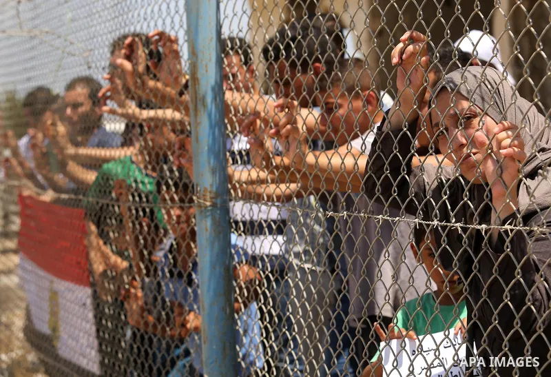 Palestinians gather in front of the gate of Rafah border crossing between Egypt and Gaza during a protest against the blockade calling for reopening of the crossing, in the southern Gaza Strip July 3, 2017. Photo by Ashr...