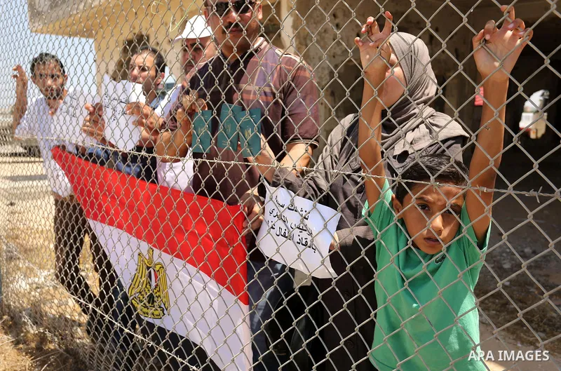Palestinians gather in front of the gate of Rafah border crossing between Egypt and Gaza during a protest against the blockade calling for reopening of the crossing, in the southern Gaza Strip July 3, 2017. Photo by Ashr...