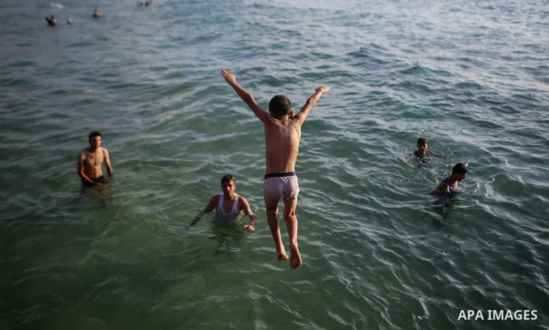 Palestinians swim in the Mediterranean sea on the coast of Gaza city during a hot day on July 3, 2017. Photo by Majd Hajjar